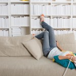 Woman on phone lying on couch w books